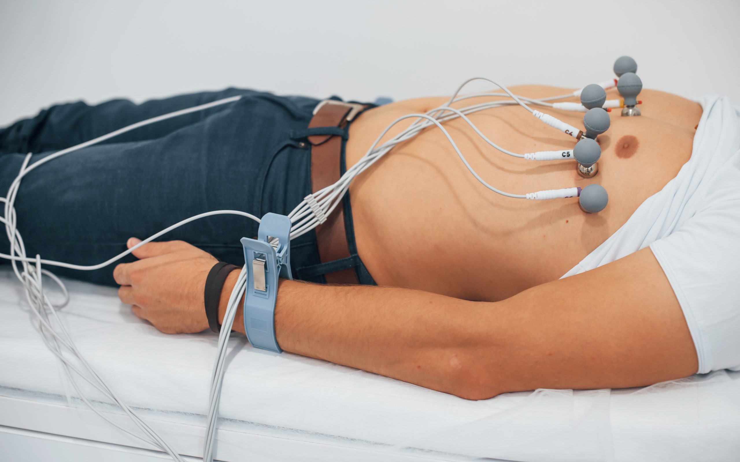 Man lying on the bed in the clinic and getting electrocardiogram test.